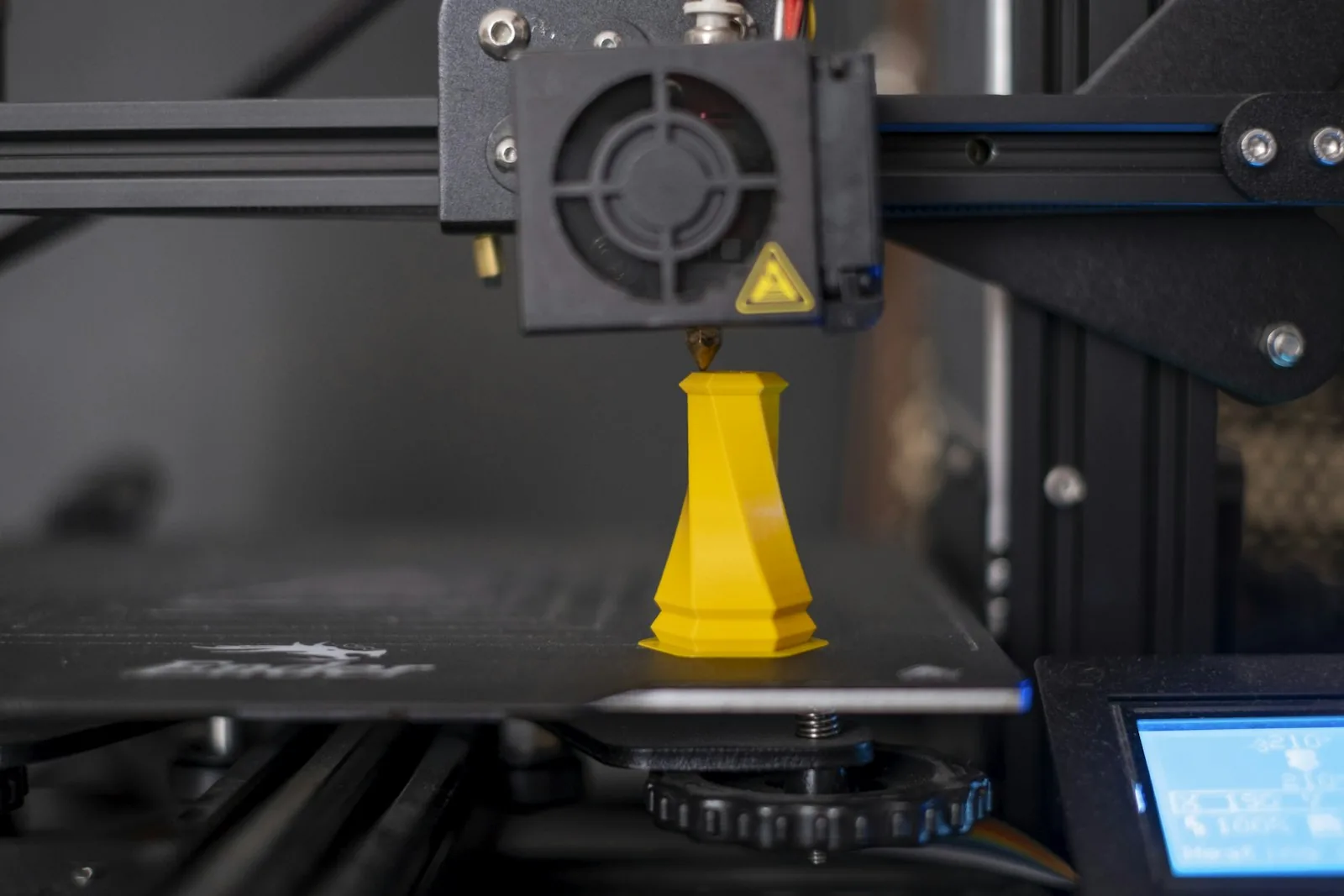 Vaso geométrico amarelo sendo impresso em 3D