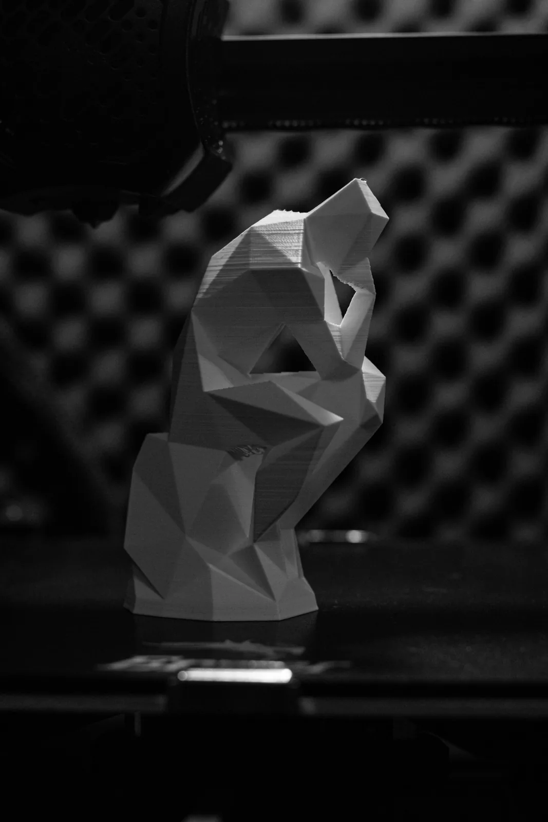 Escultura low-poly branca impressa em 3D sobre mesa escura