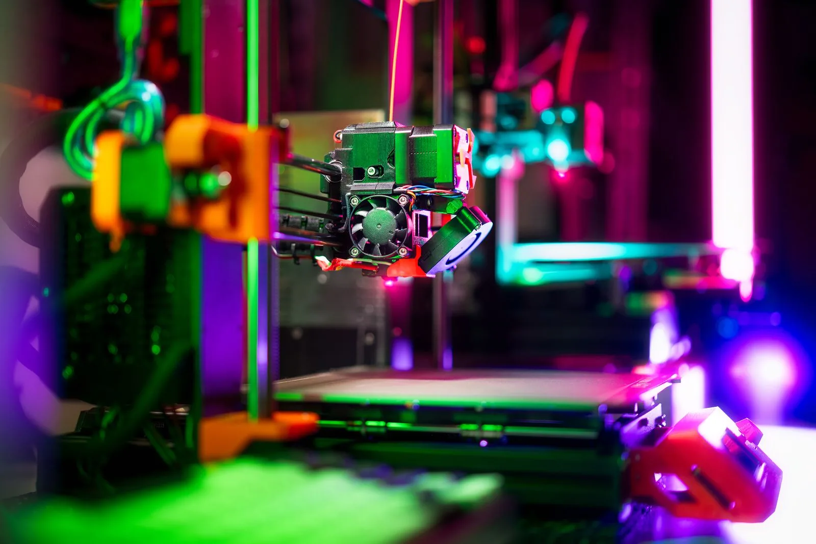 Duas impressoras 3D trabalhando sob luzes neon